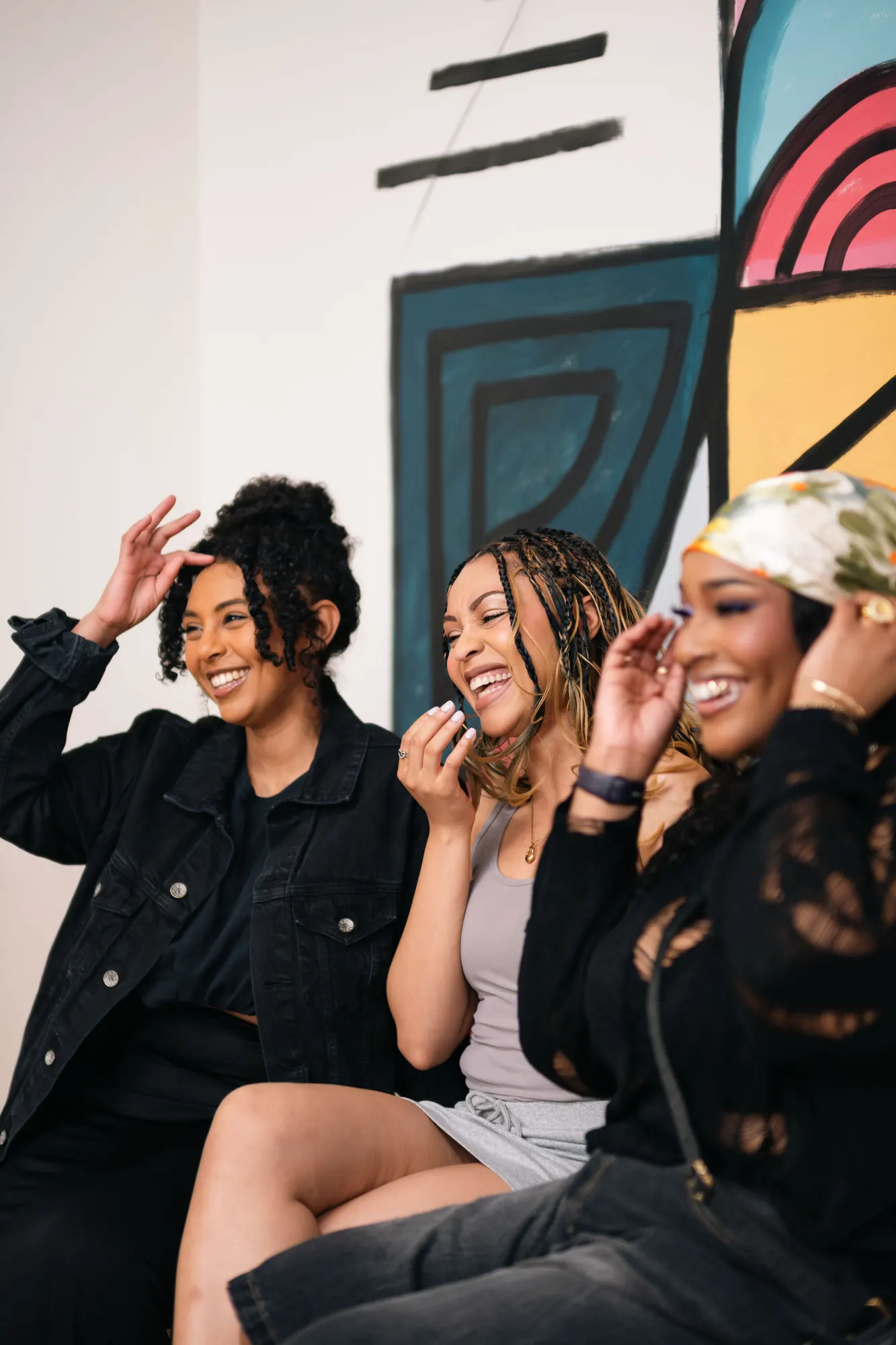 Three women laughing together on a sofa